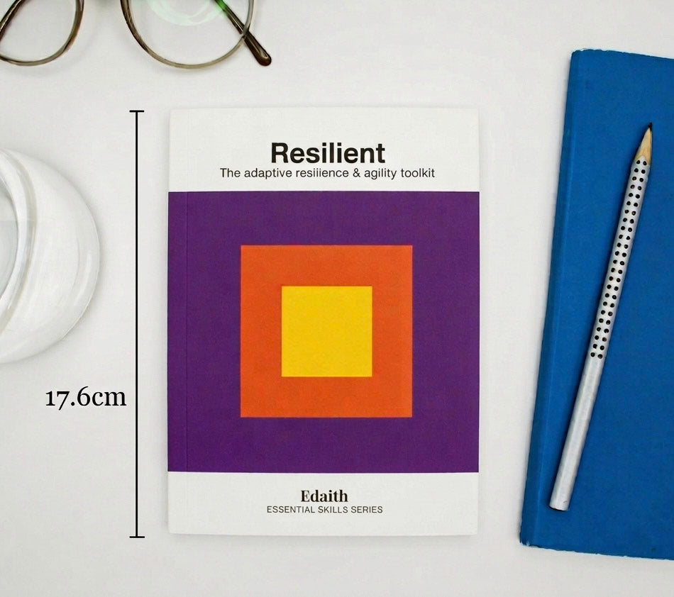 Book titled 'Resilient' by Edaith on a white surface with a pen and glasses.